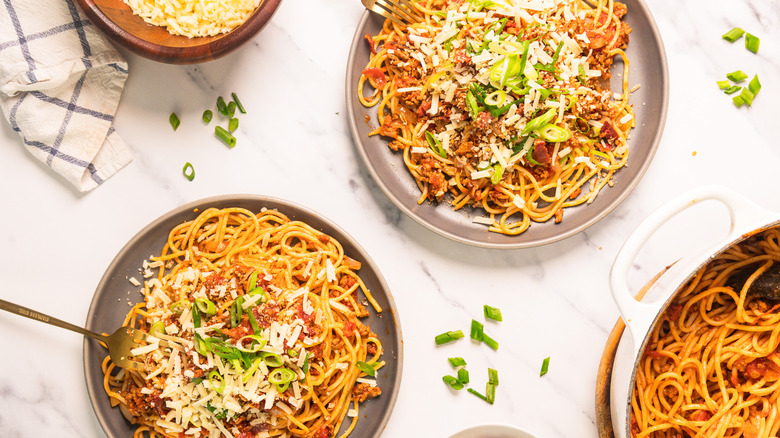 Two plates of bourbon-infused cowboy spaghetti next to big pot