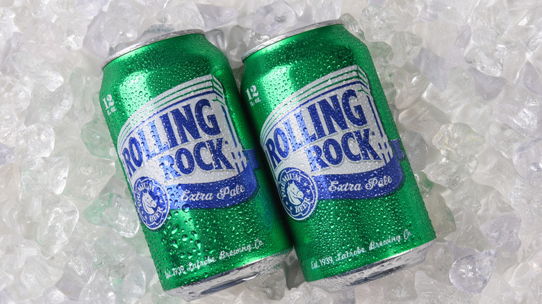 Two small cans of Rolling Rock beer on ice.