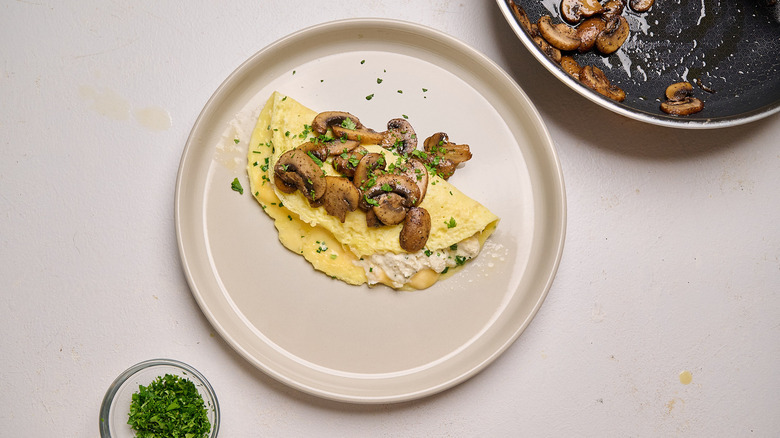 mushrooms and parsley on top of omelet on plate
