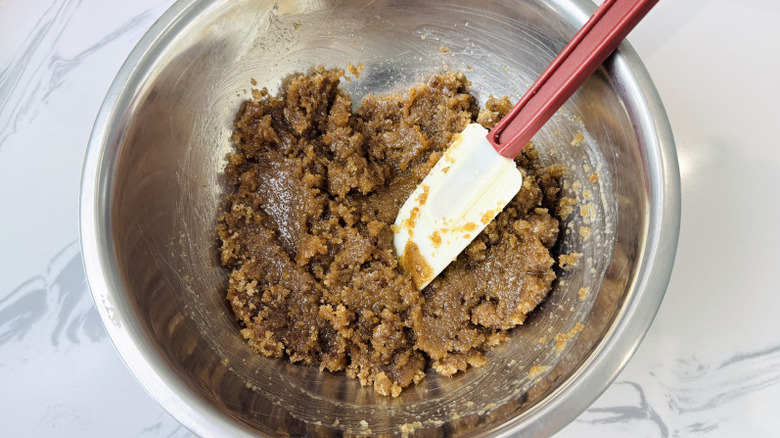 Butter and brown sugar mixture with rubber spatula in bowl
