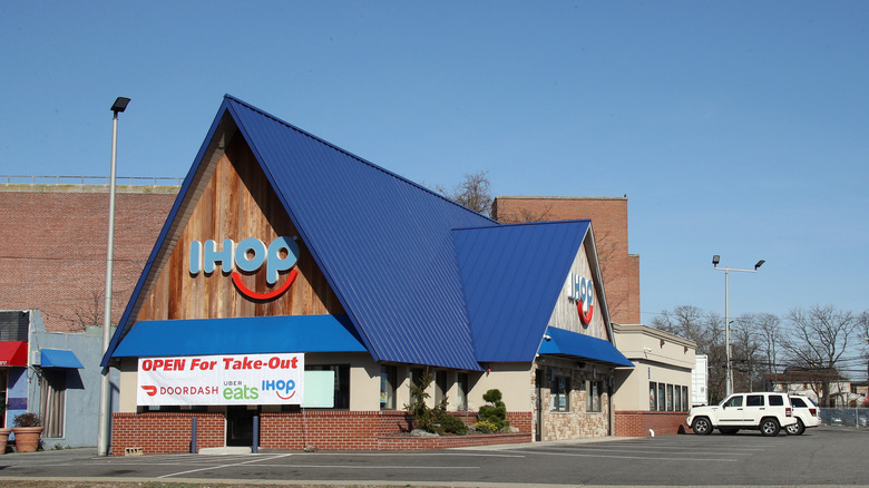 An IHOP storefront is pictured with a banner that says the location is open for food delivery.
