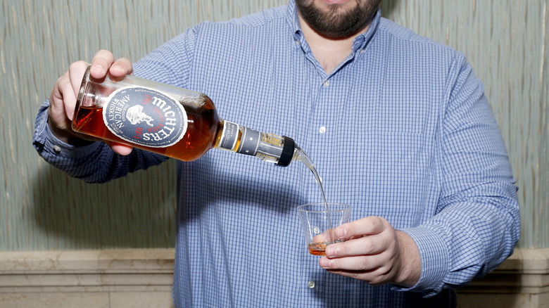 Person pouring Michter's whiskey bourbon.