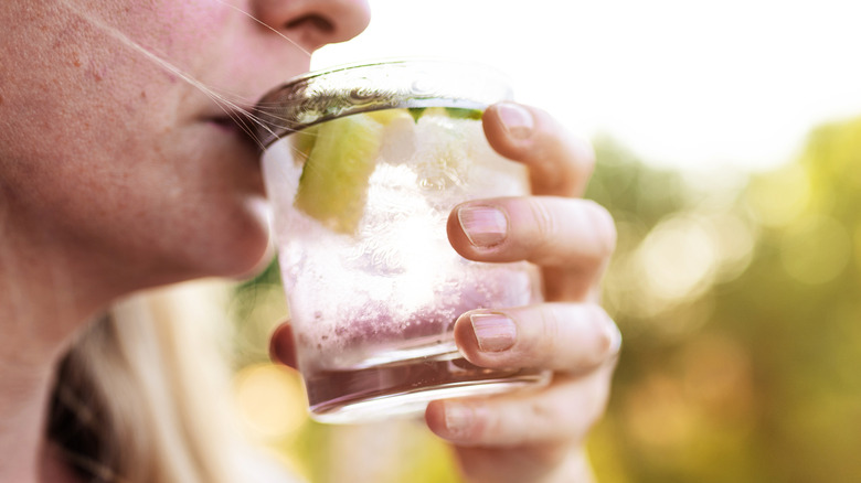 Woman sipping glass of gin with lime