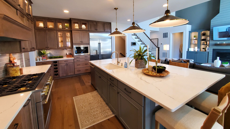 A kitchen with dark wood cabinets and a white marbled quartz countertop