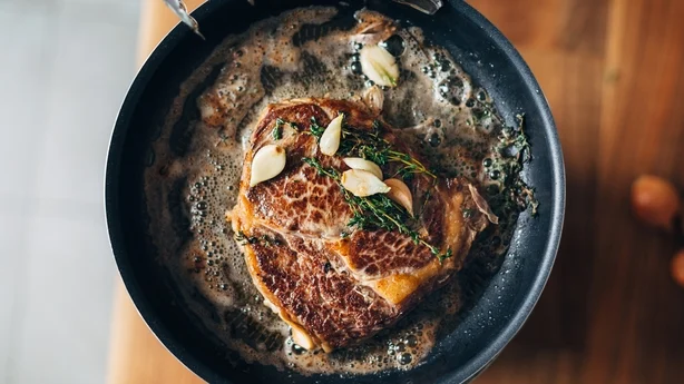 Overhead shot of chef preparing ribeye with butter, thyme and garlic. Keto diet.