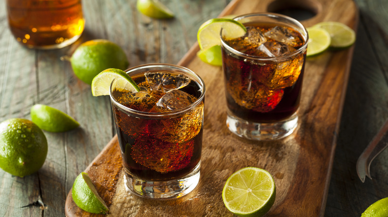 Cuba Libre cocktails on wood board with limes