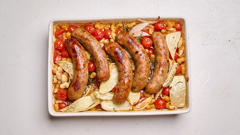 roasted sausages in a pan with roasted tomatoes