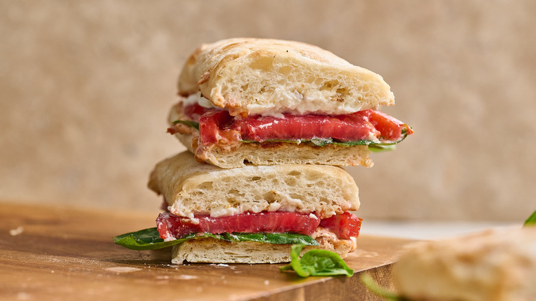 halved sandwiches stacked on a cutting board