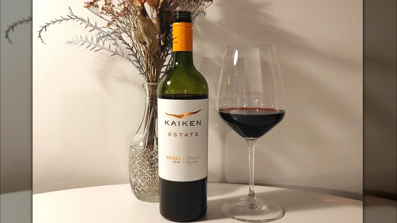 bottle and glass of wine with vase of dried flowers