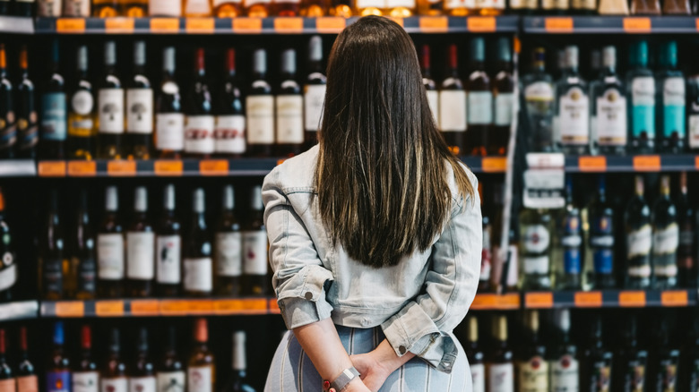 woman standing in front of wine shelves