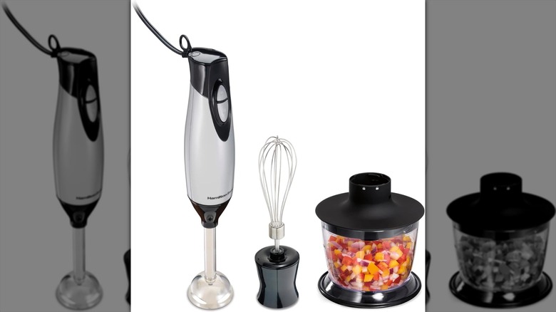 A silver electric immersion blender next to a whisk and bowl with a white background
