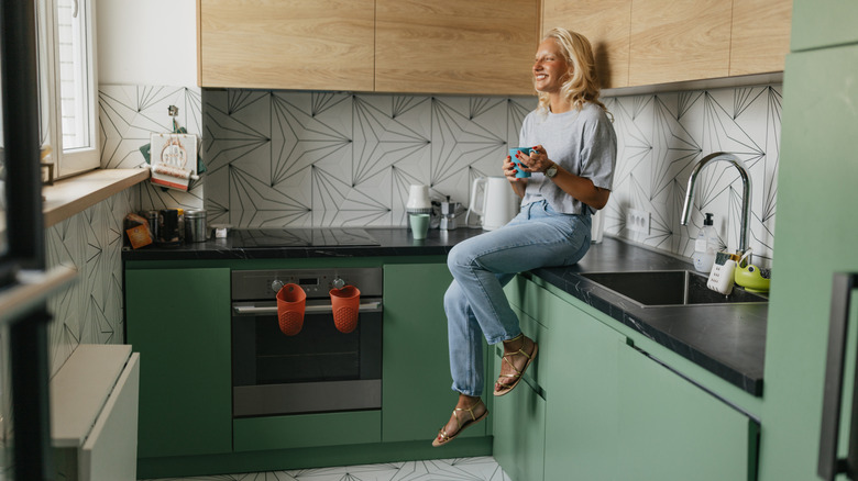 View of person sitting on the counter in a modern kitchen.