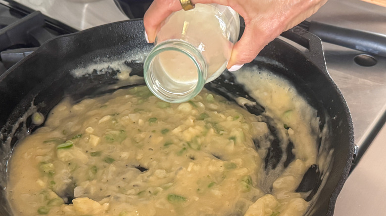 hand adding milk to skillet
