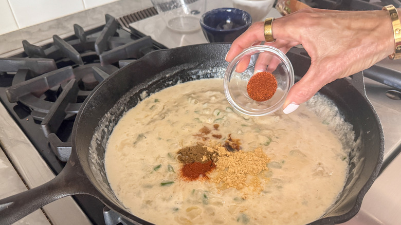 hand adding spices to skillet