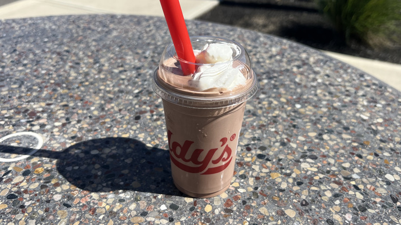 Freddy's Chocolate Shake with a straw on an outside table