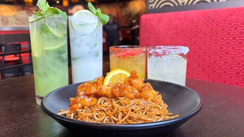 Four P.F. Chang's cocktails on a table and orange chicken in the forefront