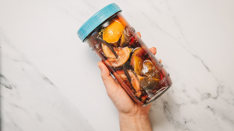 Hand holding sealed jar with infused gin
