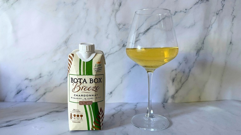 Mini Bota Box Breeze Chardonnay next to wine in glass on marble surface