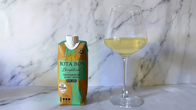 Mini Bota Box Brightside next to wine in glass on marble surface