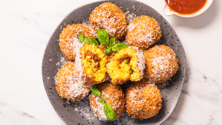 Plate of arancini alongside marinara in small bowl