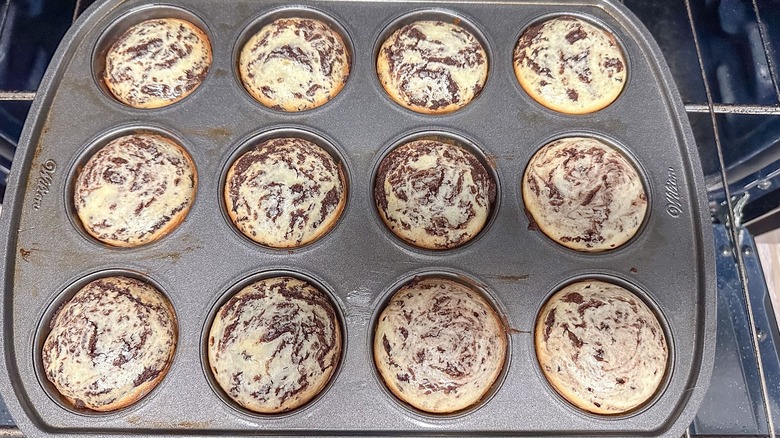 Cheesecake brookie muffins in muffin tin on oven rack