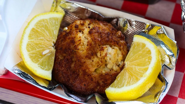 Crab cake on foil with slices of lemon