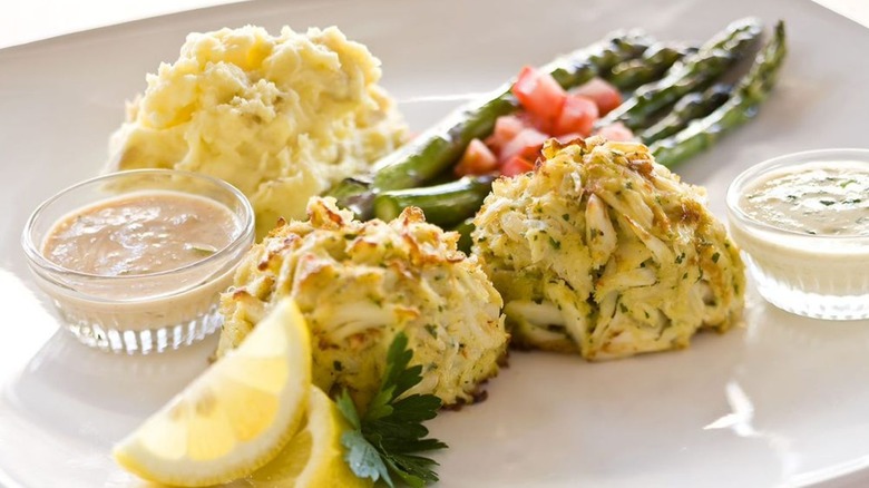 Crab cakes with lemon, sauces, asparagus, and mashed potato