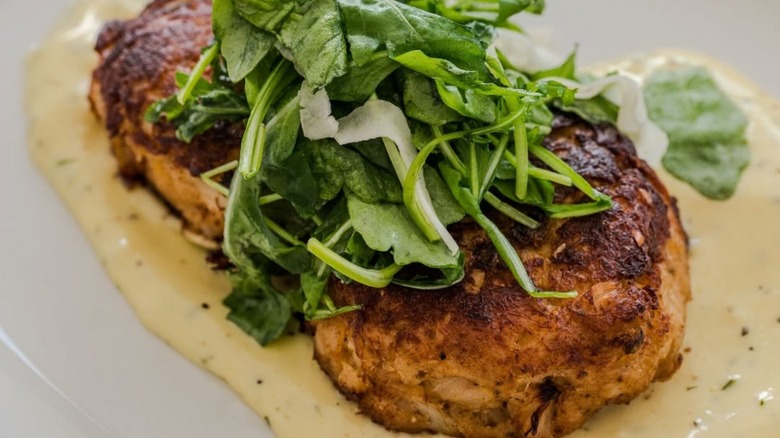 Two crab cakes with sauce and greens