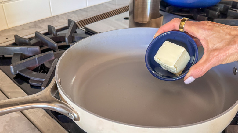 hand adding butter to pan