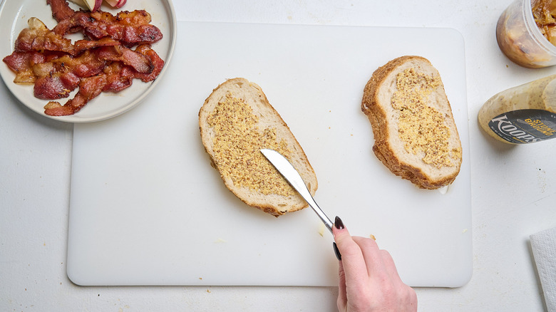 spreading mustard onto bread